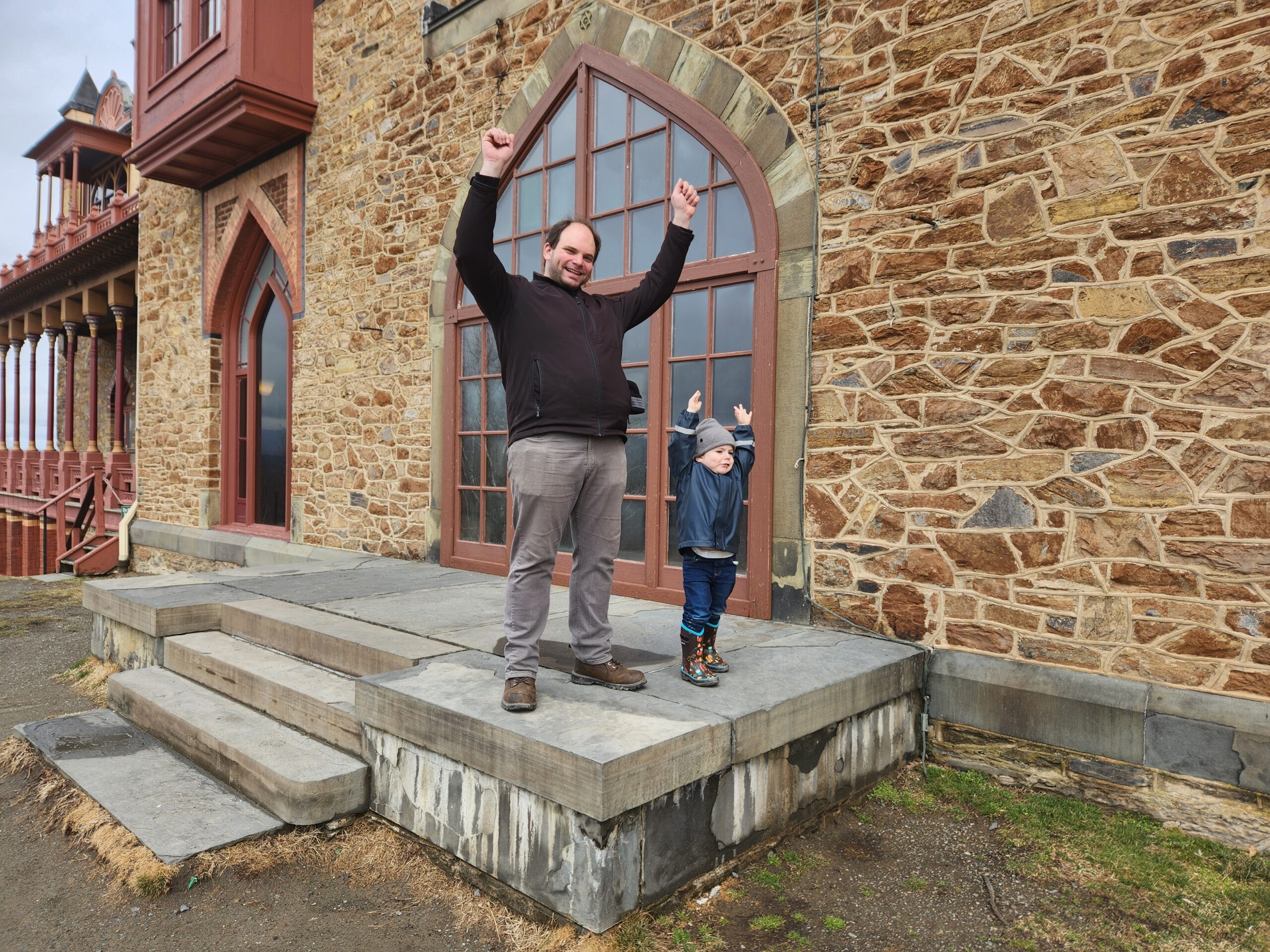 Adult and child on patio outside historic house.